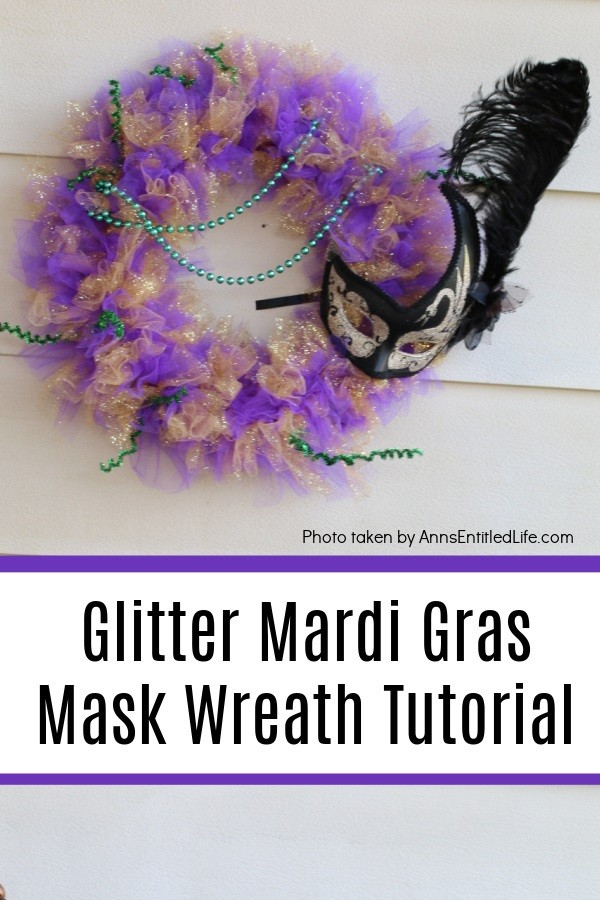 glittery purple, green, and gold Mardi Gras wreath with a black mask on the right, hanging on a hook