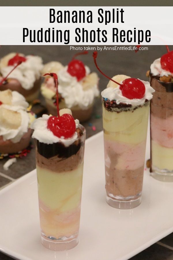 A white tray holds several clear tubes of banana split pudding shots, there are other banana split pudding shots in the background