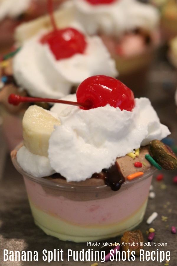 Close up of a banana split pudding shot in a souffle container, there are other banana split pudding shots in the background