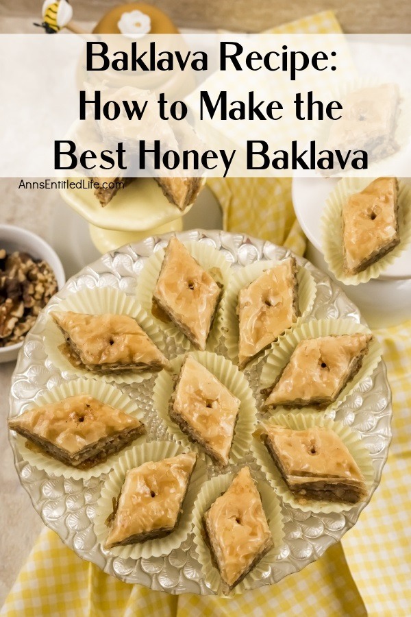 Overhead view of diamond-shaped baklava in white paper holders on a clear pastry dish, more pieces are in plates above, a honey pot is in the top left, and to the immediate left is a white plate of shelled walnuts