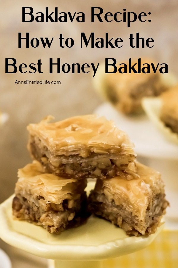 Three diamond-shaped pieces of baklava stacked in a triangle on a white pastry dish, there are several more pieces in the background