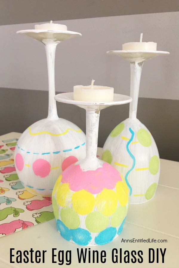 Three wine glasses painted to resemble Easter eggs sitting on a bunny matt.