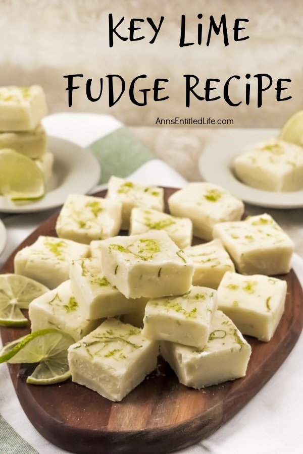 A wooden tray filled with cut squares of key lime fudge, garnished with limes. In the background are white bowls filled with more fudge