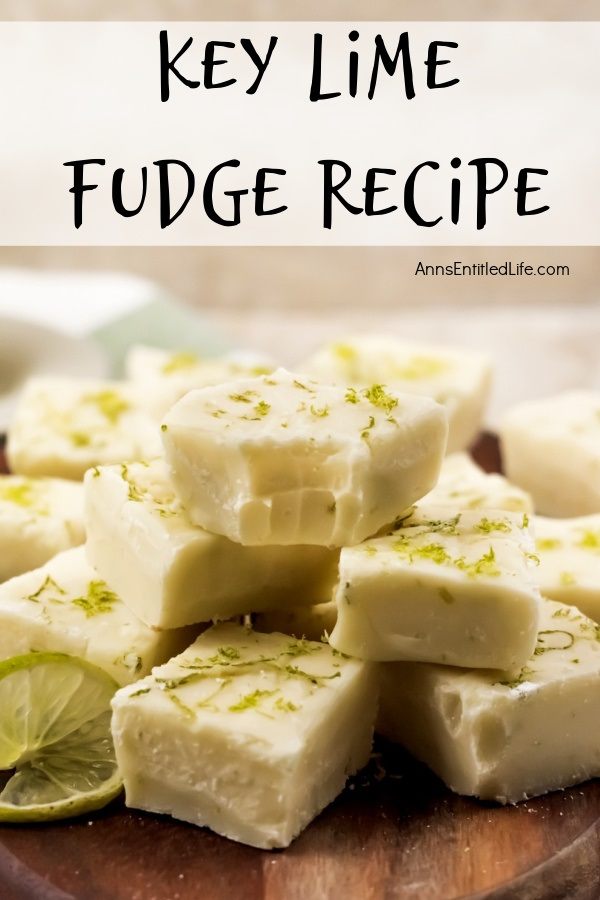 A close up of a wooden tray filled with cut squares of key lime fudge, garnished with limes. The top piece has a bite removed.