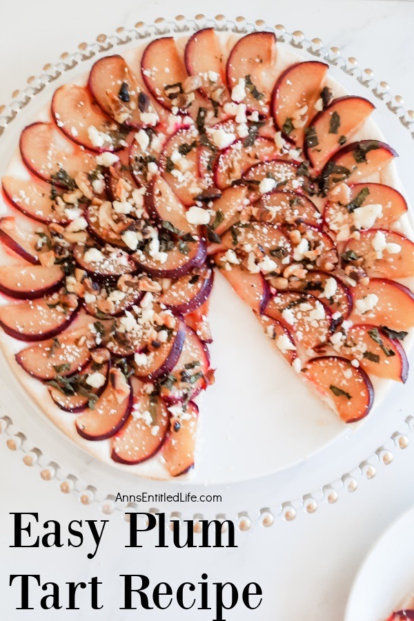 A plum tart is sitting on a clear dish, one pie wedged piece is missing