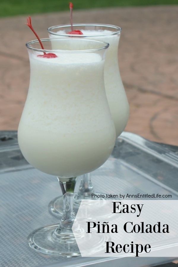 two pina colada cocktails. one behind the other, on a clear tray set atop an outdoor table in a backyard