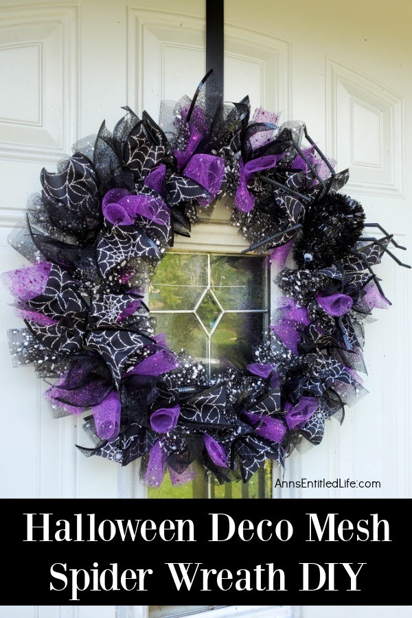 a purple and black Halloween wreath accented with spider ribbon and faux sider, hanging against a white door