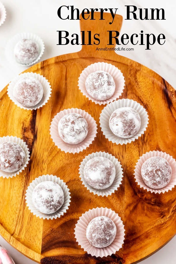 Overhead view of nine cherry rum balls in a white candy wrapper sitting on a wooden board.