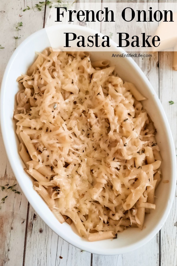 A white bowl filled with French onion pasta bake sits on a board