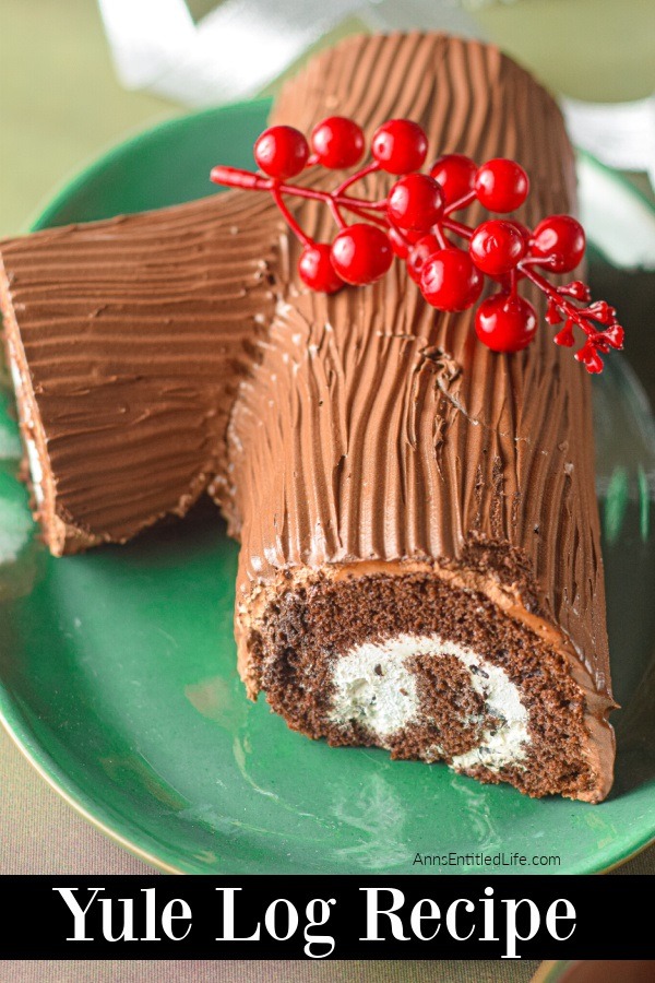 A close-up, slightly overhead view of a yule log cake on a green platter with faux cranberries adorning it