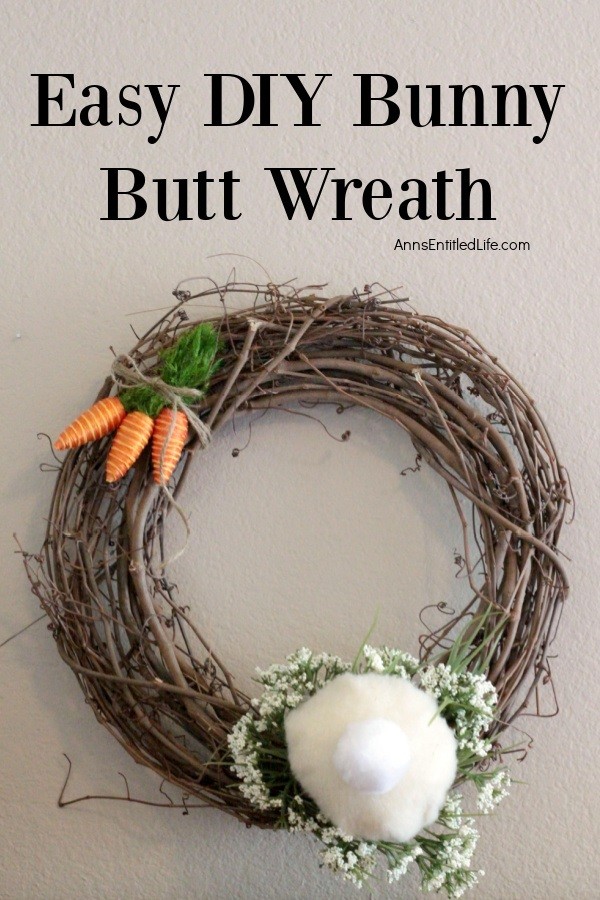 a gravevine wreath decorated to resemble a bunny butt hanging against a tan wall