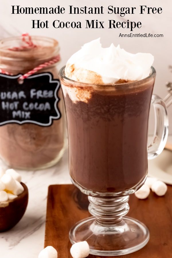 Close up of a jar of sugar free instant hot cocoa mix in the upper left, a mug is made in the lower right. In the lower left is a bowl of marshmallows