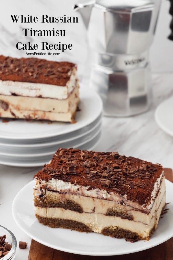 An piece of white Russian tiramisu on a white plate front and center, vertical view. A second piece is in the upper left on a stack of white plates. There is a coffee pot in the upper right.