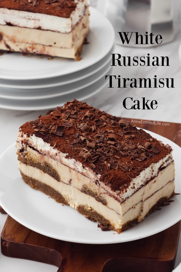An piece of white Russian tiramisu on a white plate front and center. A second piece is in the upper left on a stack of white plates. There is a coffee pot in the upper right.