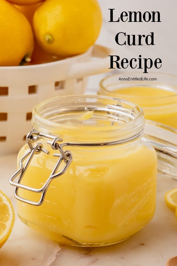 Side view of a jar of homemade lemon curd. There is a second jar in the upper right, a basket of lemons in the upper left.
