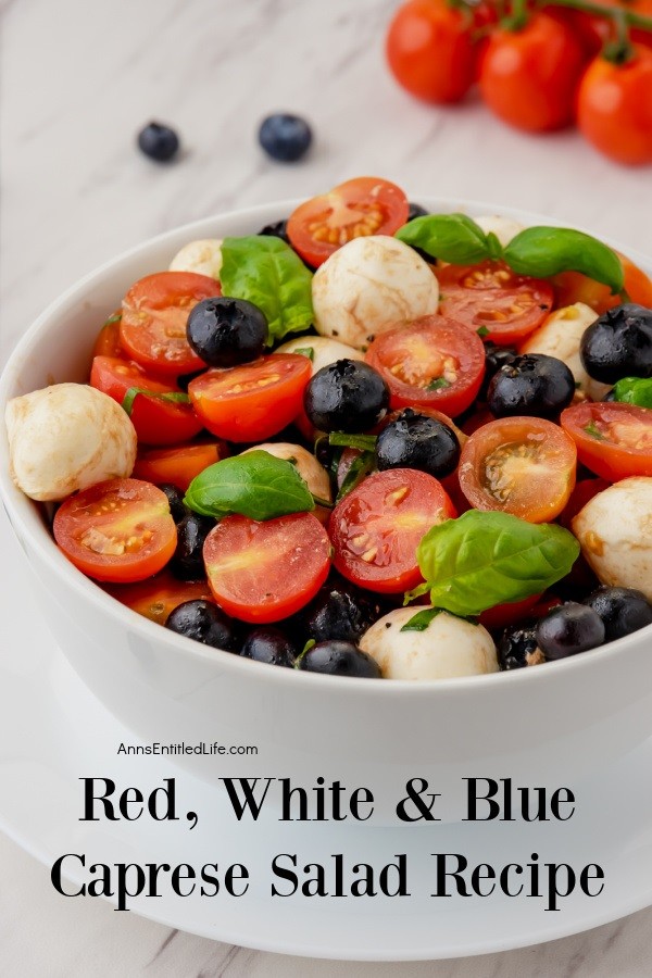 A closeup side view of the mozzarella, blueberries, basil, and balsamic glaze in a red, white, and blue Caprese salad in a white bowl