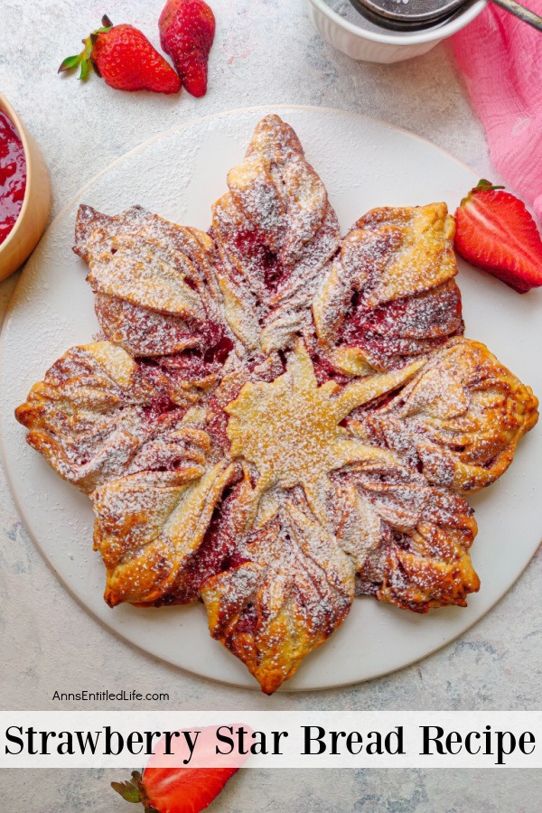 Overhead view of a strawberry bread in the shape of a star on a white plate. Fresh, sliced strawberries garnish the plate.