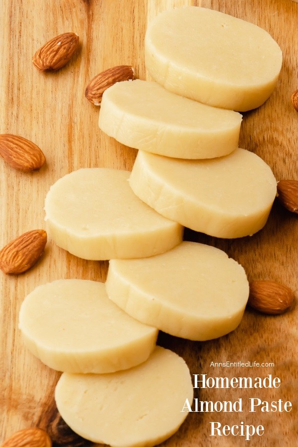Slices of almond paste on a wooden cutting board surrounded by almond nuts.