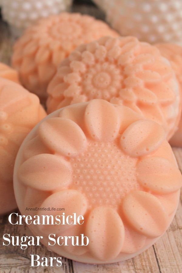 upclose image of 6 creamsicle sugar scrub bars on a wooden board. Three small pieces of milk glass are in the background 