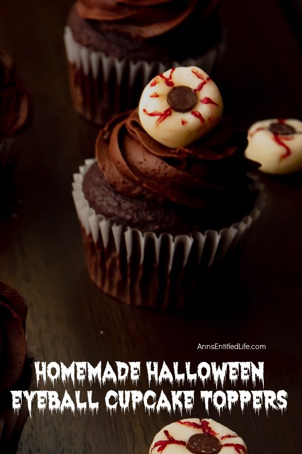 One Halloween eyeball cupcake is set against a dark background, several eyeball toppers surround the cupcake