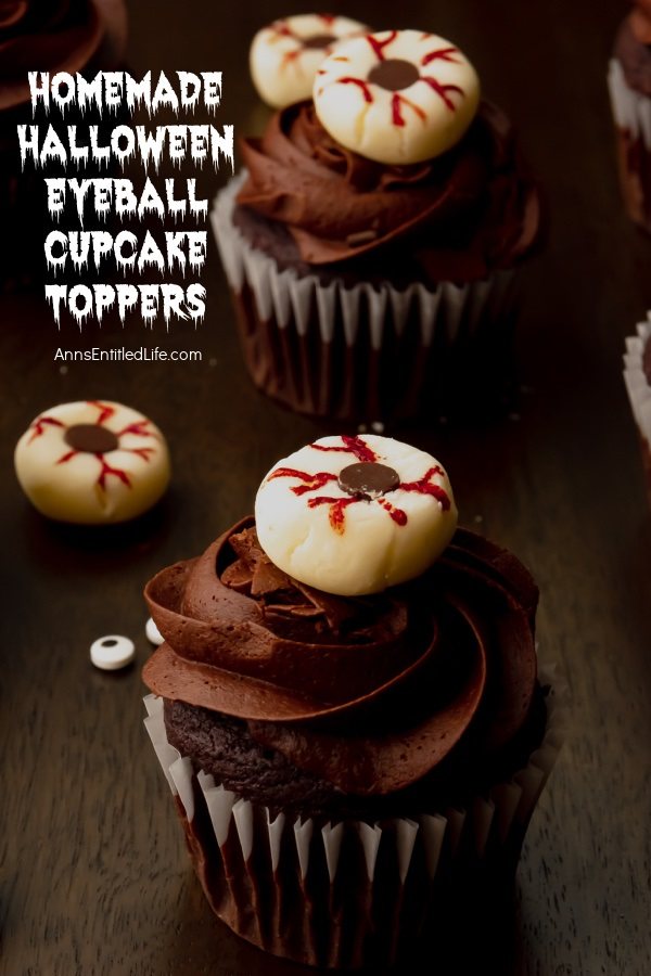 Two Halloween eyeball cupcakes against a dark background, several eyeball toppers surround the cupcakes