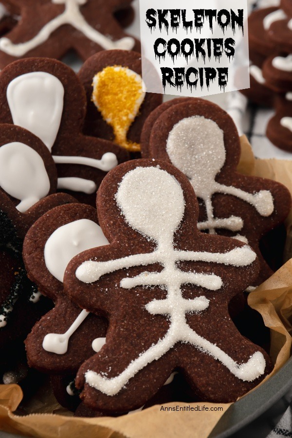 An up-close image of a a bowl filled with chocolate cookies in a skeleton shape with skeleton decorations