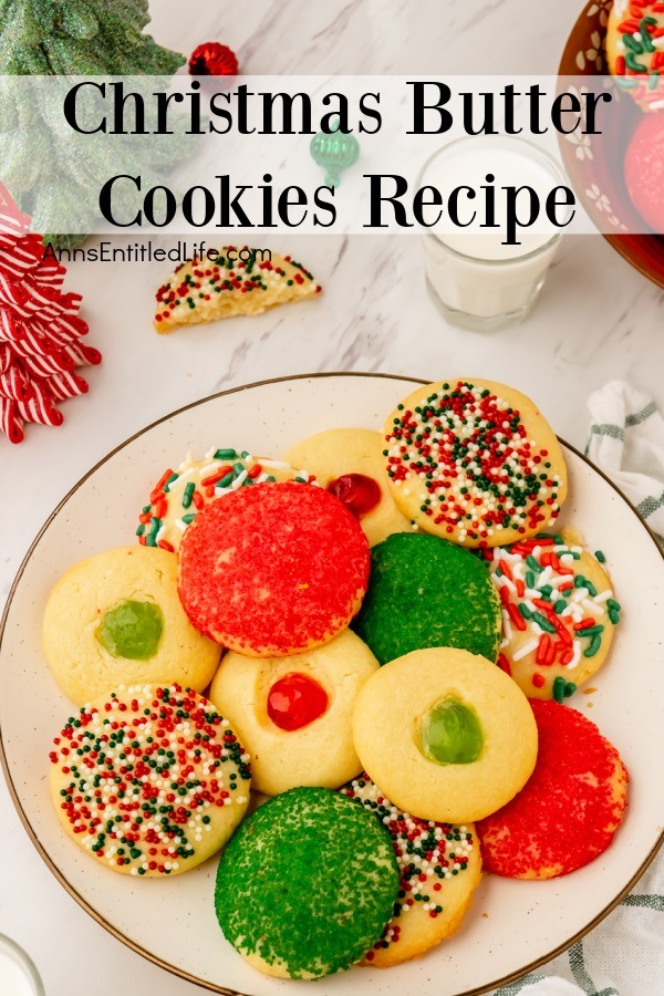 Overhead image of a white plate filled with Christmas butter cookies surrounded by Christmas decorations. There is a glass of milk in the upper right.