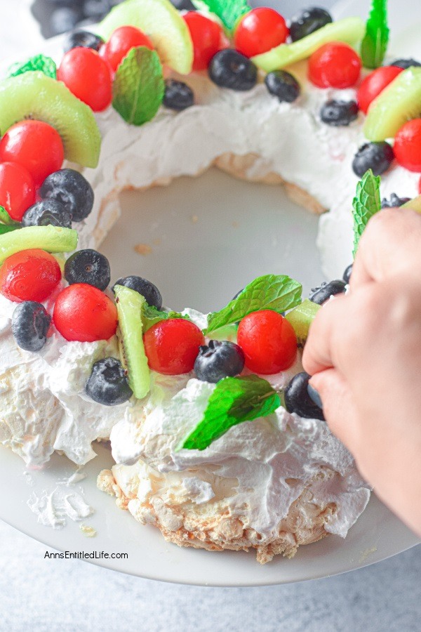 Christmas Pavlova Recipe. Pavlova is a meringue-based dessert with a crispy top and a soft, marshmallow-like center. This Christmas pavlova is topped with a generous amount of sweet vanilla whipped cream and sliced fruits and berries, which makes this classic dessert absolutely delectable. This wreath-shaped pavlova is perfect for Christmas day and is a real crowd-pleaser.