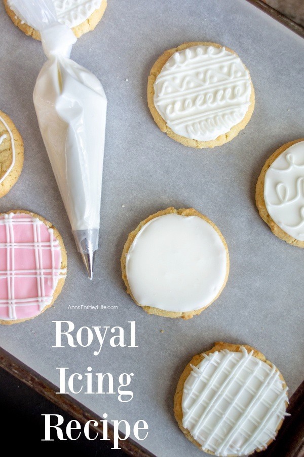 Cookies frosted with royal icing on a lined baking sheet, a pastry bag of royal icing sits in the middle of the cookies