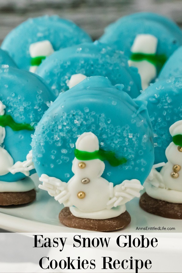 Six snowman snow globe cookies standing on a white surface