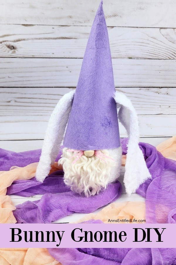 a homemade bunny gnome against a grey background, sitting on orange and purple scarves