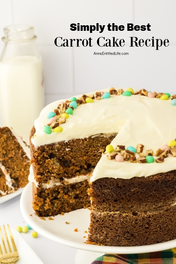 A cut away view of a carrot cake on a white cake stand. The piece of cake is in the upper left on a white plate, a bottle of white milk is behind that