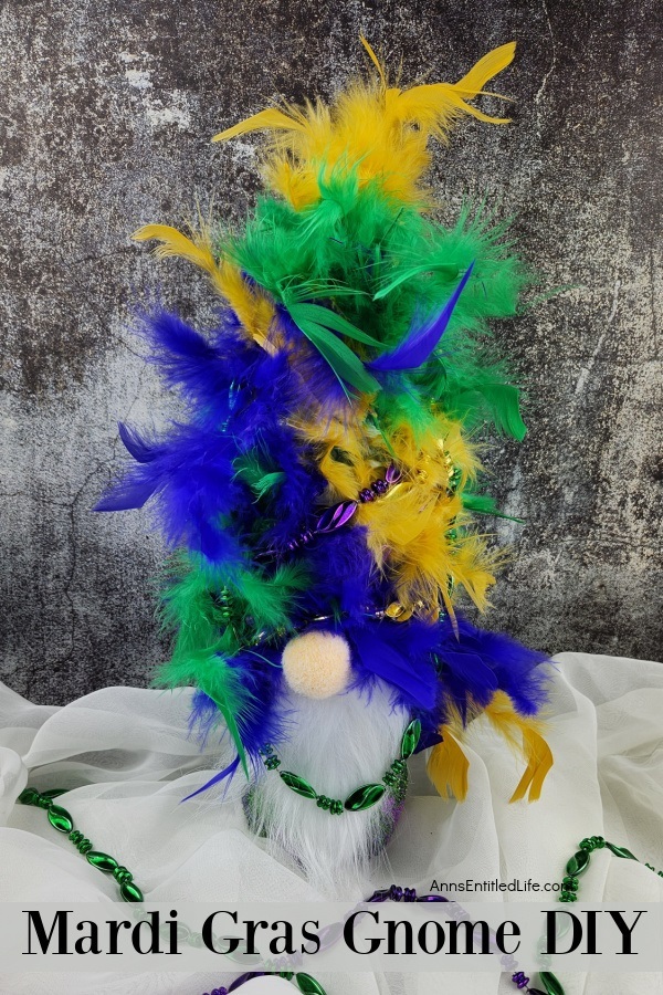a homemade mardi gras gnome on a chiffon base, dark background, colored beads on the material