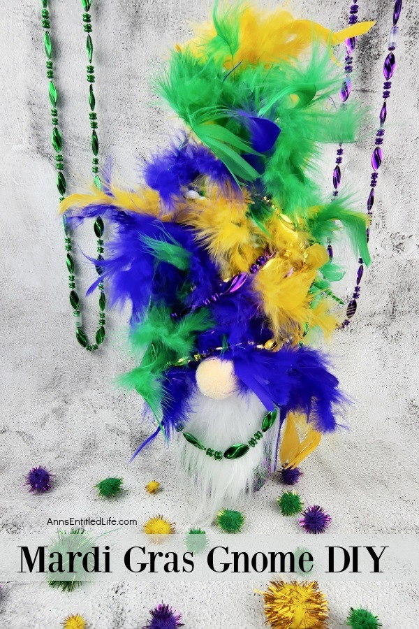 a homemade mardi gras gnome on a marble top, colored beads hanging in the background, colored pompoms on the tabletop