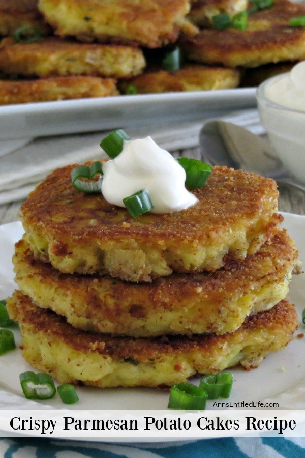 Close-up of a stack of Parmesan potato cakes on a white dish, there is a tray filled with more potato cakes in the back