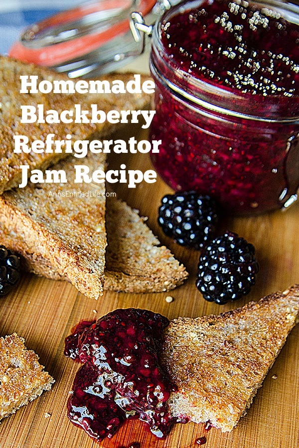 blackberry jam on a piece of taste with another stack of toast in the upper left, the homemade blackberry jam pot in the upper right, and some fresh blackberries surrounding them, on a cutting board