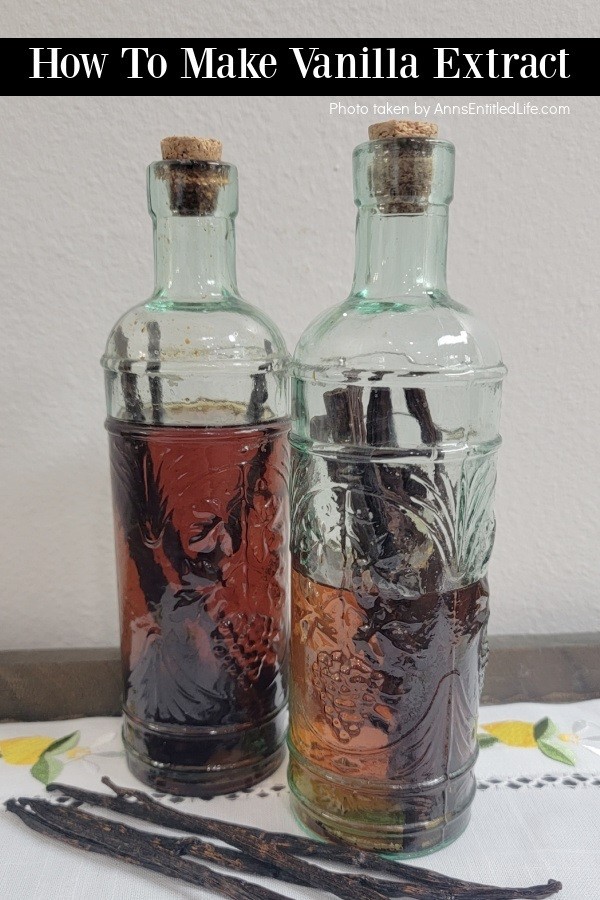 Two bottles of aged vanilla extract on a white place mat. There are five vanilla beans in front of the bottles