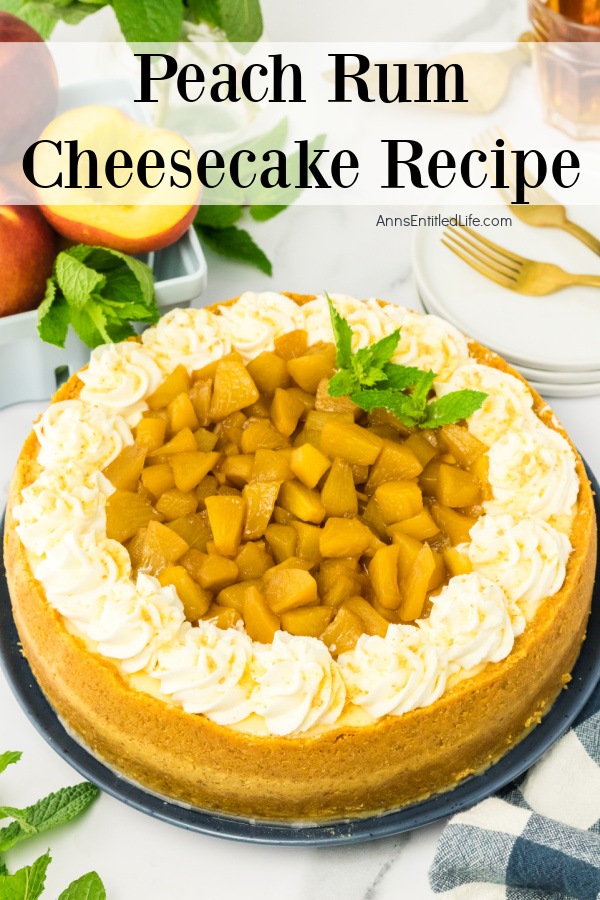 A whole peach rum cheesecake on a blue plate. There are a few fresh peaches in the upper left, plates, and forks in the upper right.