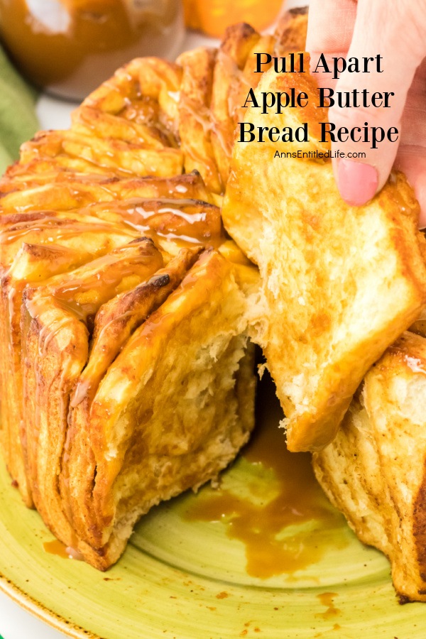 A close-up of a pull-apart apple butter bread on a green plate with a female hand pulling a piece away.