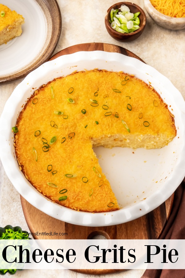 an overhead view of a white pie plate with cheesy grits inside, one piece removed. There is green onions and shredded cheese in the upper right, the removed piece on a plate in the upper left.