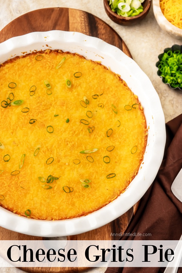 Overhead view of a white pie dish filled with baked cheesy grits. There is green onions and shredded cheese above it.