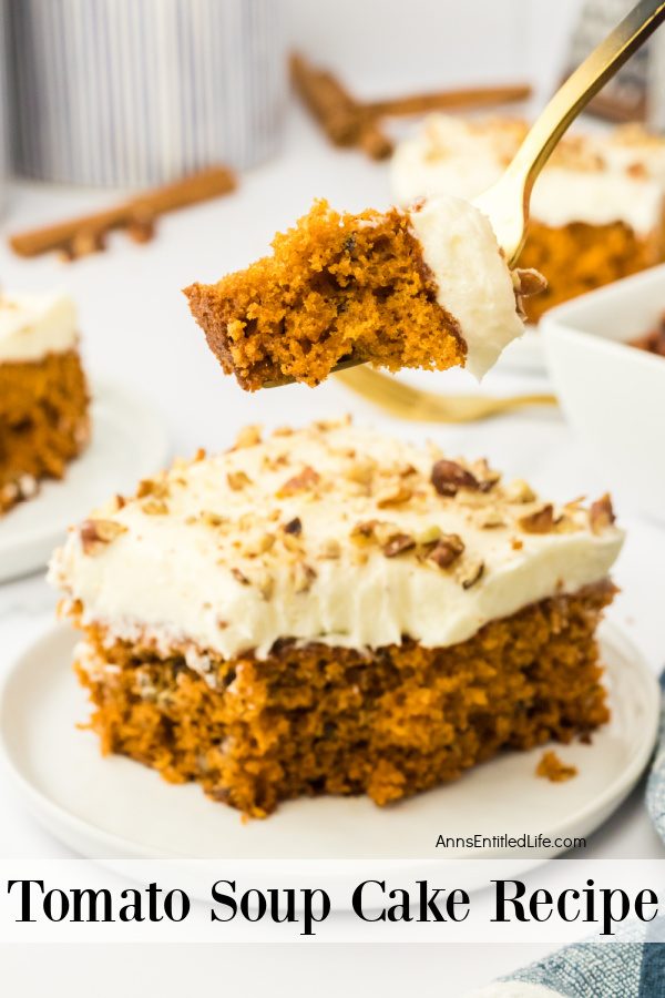 A servings of tomato soup cake is on a white plate, a piece of the cake is being lifted overhead on a gold fork. In the background is the rest of the cake in the baking pan.