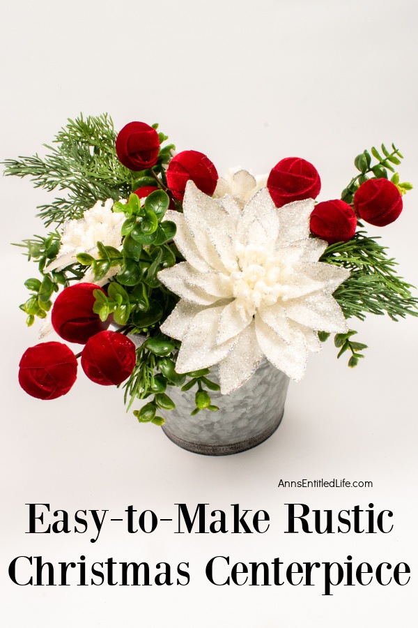A rustic farmhouse style floral holiday arrangement in a tin bucket against a white background.