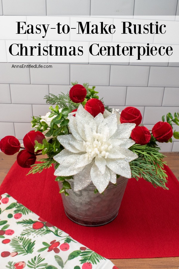 A rustic farmhouse style floral holiday arrangement in a tin bucket sits atop a red place mat against a white brick counter.