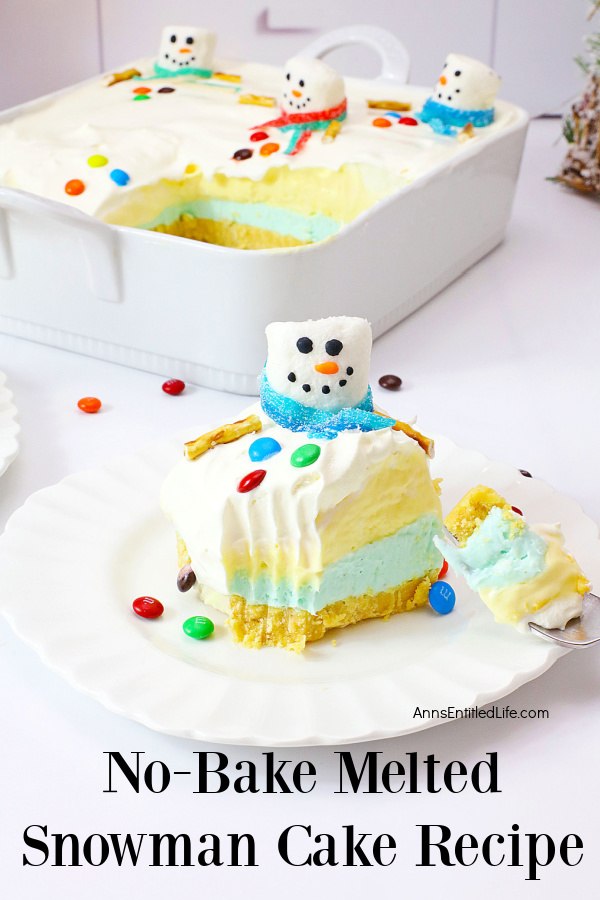 A piece of no-bake melted snowman cake sits on a white plate at the forefront, the rest of the cake is in the back. This sits on a white countertop.