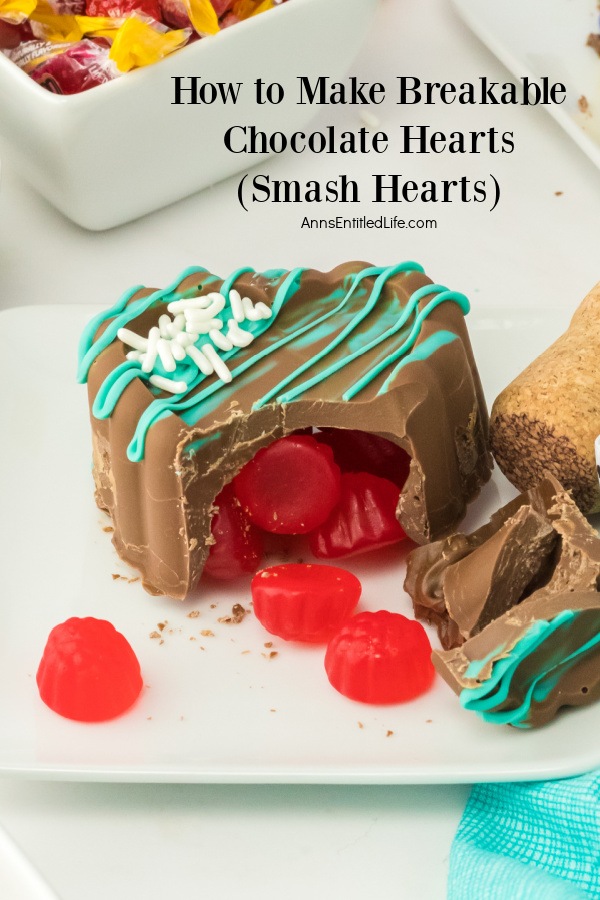 A broken milk chocolate heart sits on a white plate. Juju candies are spilling out of it.