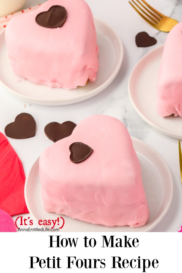 Three pink, heart shaped petit fours on white plates, there are thin chocolate hearts on the white tablecloth surrounding the cakes.