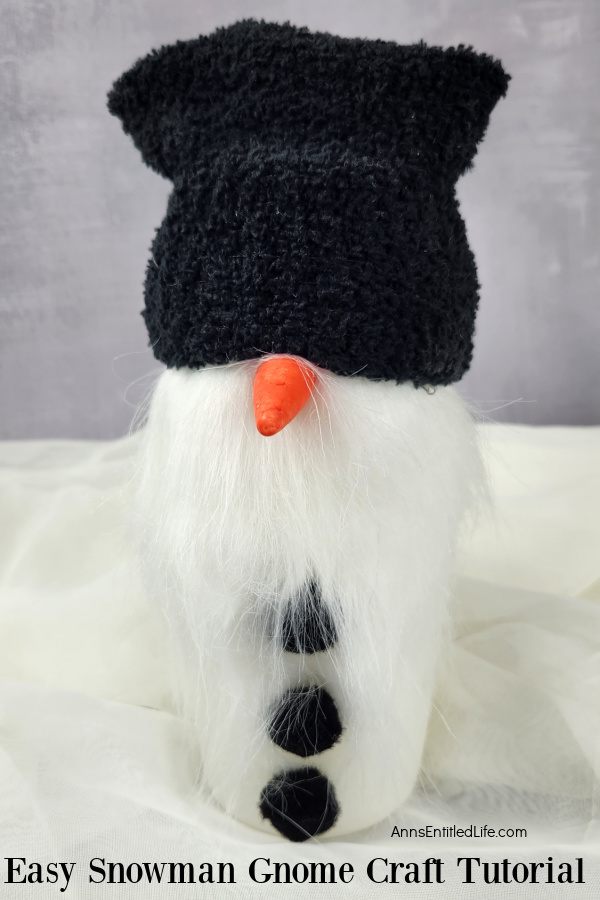Homemade snowman gnome set against a grey background, set on top of a white fabric