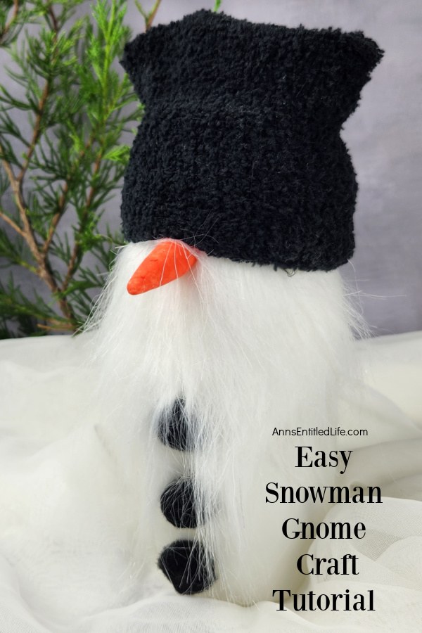 Homemade snowman gnome set against a grey background and evergreen tree