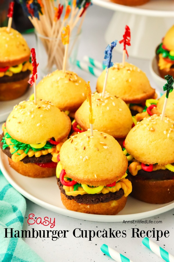 Seven cupcakes assembled to look like hamburgers sitting on a white plate. There is an either cupcake in the upper left